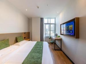 a hotel room with a large bed and a tv at GreenTree Inn Express Lanzhou West Passenger Station Lanzhou Center in Lanzhou