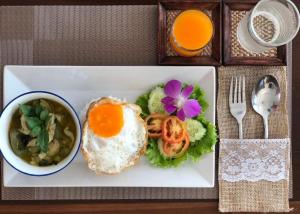 a plate of food with an egg and vegetables and a bowl of soup at KOKHABURI HOTEL in Ban Chomphu