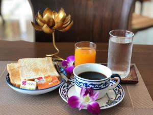 a table with a cup of coffee and a plate of food at KOKHABURI HOTEL in Ban Chomphu