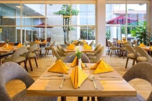 un restaurant avec des tables et des chaises en bois et des serviettes jaunes dans l'établissement Horison Hotel Ultima Timika, à Timika