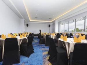 une salle de banquet avec tables et chaises et sièges jaunes dans l'établissement Horison Hotel Ultima Timika, à Timika