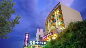 un edificio alto con letreros de neón delante de él en Gangneung Four Season Hotel and Pension, en Gangneung
