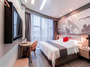 um quarto de hotel com uma cama, uma mesa e uma televisão em Thank Inn Guizhou Bijie Qianxi County High-Speed Railway Station em Qianxi
