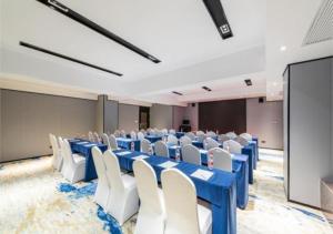 Echarm Hotel Liuzhou Liunan Wanda Plaza Liuyong Road في ليوشو: قاعة المؤتمرات مع الطاولات الزرقاء والكراسي البيضاء