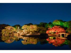 a reflection of trees in the water at night at Tora Hotel Rikugien in Tokyo