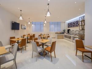 a restaurant with tables and chairs and a kitchen at City Comfort Inn Wuzhou Xijiang Thrid Bridge in Cangwu