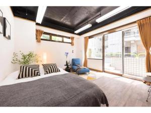 um quarto com uma cama grande e uma cadeira azul em Tora Hotel Rikugien em Tóquio