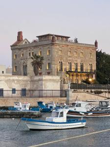 a group of boats docked in the water in front of a building at La Corte di Greta in Favignana