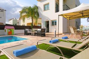 een patio met 2 ligstoelen en een zwembad bij Villa Summer in Protaras