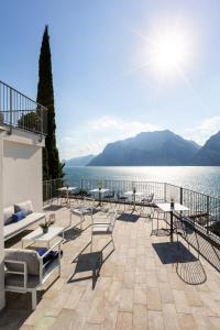 a patio with tables and chairs next to a body of water at VistaLago Torbole in Nago-Torbole