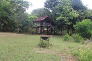 a house in a field with a grill in front of it at Eagles Wing's GuestHouse in Habarana