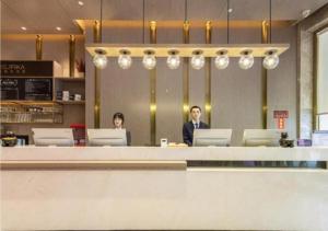 dos personas sentadas en un mostrador en un restaurante en Premier City Comfort Hotel Quanzhou Wanda Plaza, en Donghai