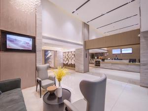 a lobby with a waiting area with a tv and chairs at City Comfort Inn Wuzhou Sanqi City Rose Lake Park in Wuzhou