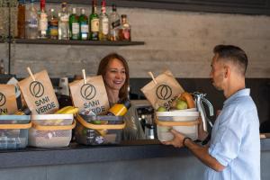 a man and a woman standing behind a counter with food at Sani Verde in Sani Beach