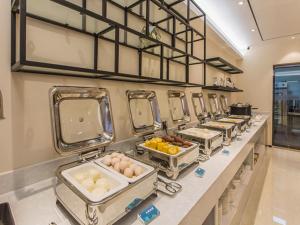 a row of buffet tables with eggs and other foods at City Comfort Inn Wuzhou Sun Plaza Wanda in Wuzhou