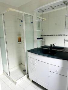 y baño blanco con lavabo y ducha. en Maison de l'Anse, plage à 100m en Névez