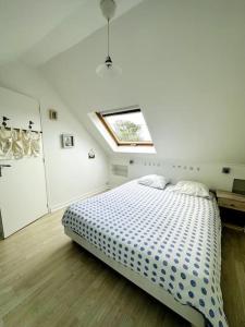 Dormitorio blanco con cama y tragaluz en Maison de l'Anse, plage à 100m en Névez