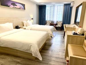 a hotel room with two beds in a room at JTOUR Inn Maoming Huazhou Beijing Road Railway Station in Sanguantang