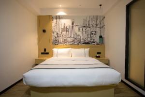um quarto com uma grande cama branca com um quadro na parede em City Comfort Inn Huaihua East Station em Huaihua