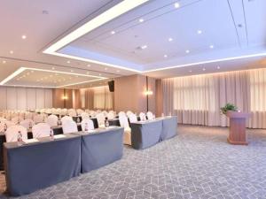 una sala de conferencias con mesas y sillas y un podio en GreenTree Eastern Hotel Nanning Wuxiang Hangyang City, en Nanning