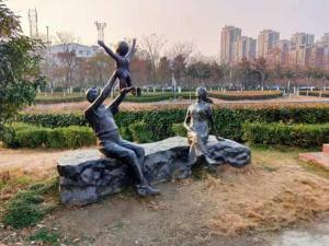 Una statua di tre persone seduta su una roccia di Green Tree Inn Express Anhui Bozhou Mengcheng County Chengnan New District a Zhuangzhou