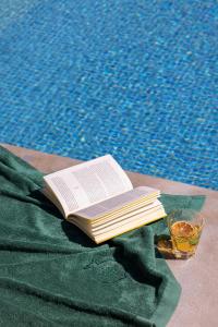 a book sitting on a table next to a pool at Palacio Solecio, a Small Luxury Hotel of the World in Málaga