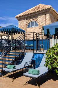 Palacio Solecio, a Small Luxury Hotel of the World في مالقة: مسبح مع كرسيين للصاله ومظلات