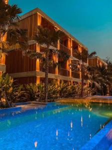 a swimming pool in front of a building with palm trees at Riverton Hotel in Samut Songkhram