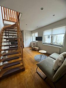 a living room with a staircase and a couch at Hello Noordwijk - Zomerhuis Quarles van Uffordstraat 89 in Noordwijk