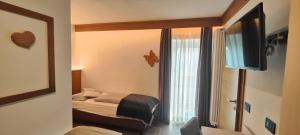 a small bedroom with a bed and a window at Hotel Aida in Pozza di Fassa