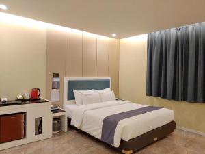 a bedroom with a large white bed and a tv at jeju illua hotel in Jeju