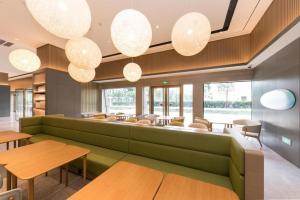 a lobby with a green couch and tables and chairs at Ji Hotel Shanghai Hongqiao Gubei Fortune Center in Shanghai