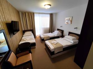 a hotel room with three beds and a television at Hotel Sun in Senec