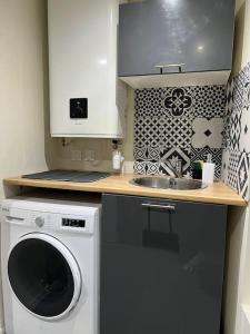 uma cozinha com uma máquina de lavar roupa e um lavatório em House BLUE. close of Stade de France. em Stains