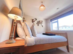 1 dormitorio con 1 cama con lámpara y ventana en Cosy House Close To Stunning Beaches en Braunton