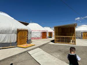 Traditional Yurts - Ulgii Guest House في أولجي: صبي صغير يقف أمام مجموعة من الخيام
