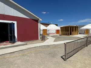 un edificio rosso con recinzione e alcune tende di Traditional Yurts - Ulgii Guest House a Ölgiy