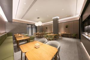 un restaurant avec des tables en bois et des chaises vertes dans l'établissement Ji Hotel Gu'an Daxing International Airport, à Gu'an