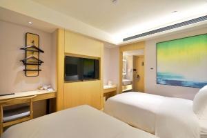 Cette chambre comprend 2 lits et une télévision à écran plat. dans l'établissement Ji Hotel Gu'an Daxing International Airport, à Gu'an