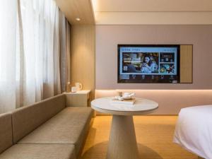pokój hotelowy ze stołem i telewizorem na ścianie w obiekcie Ji Hotel Hangzhou West Lake Hubin Erqing Building w mieście Hangzhou