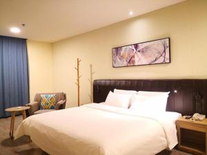 a bedroom with a large white bed and a chair at Hanting Hotel Datong Xihuan Road in Datong