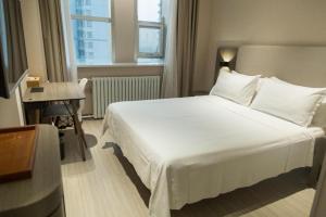 a bedroom with a large white bed and a desk at Hanting Hotel Heze Zhonghua Road Ginza in Heze