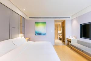 a white bedroom with a large bed and a television at JI Hotel Wenzhou South Railway Station in Louqiao