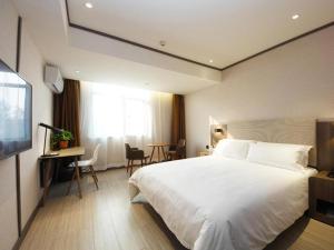 a bedroom with a large white bed and a desk at Hanting Hotel Hefei Baoye Dongcheng Plaza in Hefei