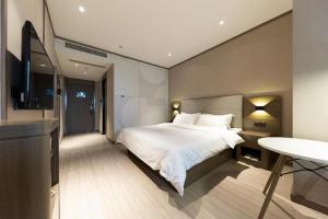 a bedroom with a bed and a flat screen tv at Hanting Hotel Hefei Baoye Dongcheng Plaza in Hefei