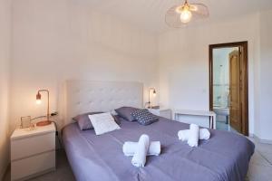 Un dormitorio con una cama morada con toallas. en SeaHomes Vacations - VILLA ROYER, en Tordera