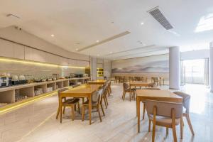 a restaurant with tables and chairs and a kitchen at Ji Hotel Wuhan Guanggu Software Park Minzu Avenue in Liufangling