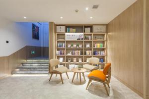 a library with chairs and a table and books at Hanting Premium Hotel Ji'nan Quancheng Road in Jinan