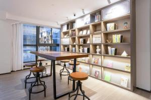 a library with a table and stools in front of a book shelf at Hanting Hotel Ji'an Chengnan Administrative Center in Ji'an