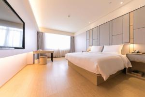 a bedroom with a large white bed and a table at Ji Hotel Ordos Wanzheng Plaza in Zhaoyoufang